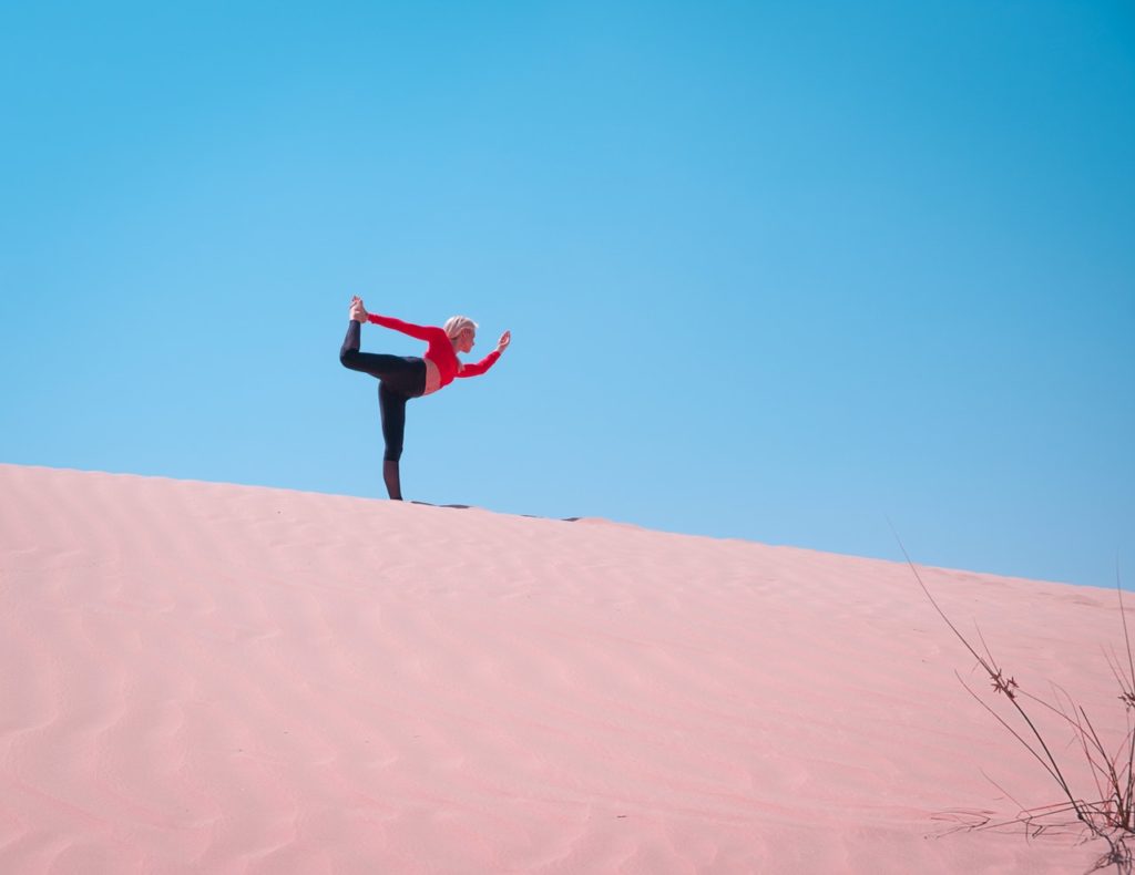 Athletic woman doing yoga in a sand